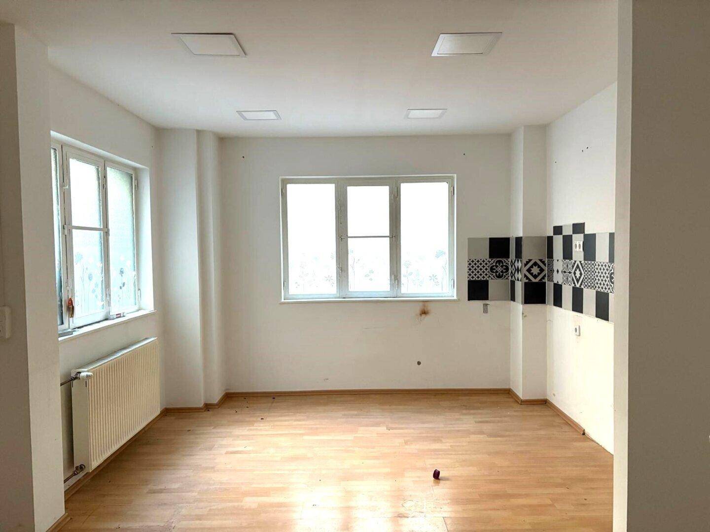 Heller Raum mit Holzfußboden und schwarz-weiß gefliestem Wandbereich, ideal für eine Küche oder Essbereich.