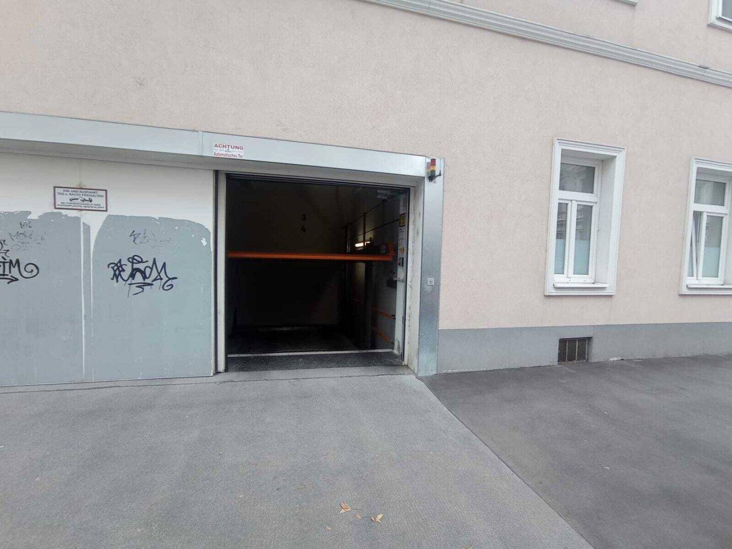 Einfahrt zur automatischen Tiefgarage mit Rampe und Hinweisschildern.