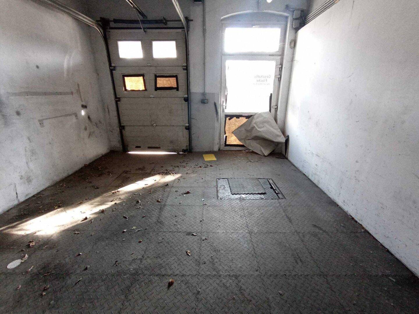 Geräumige Garage mit Rolltor, Betonboden und einer Wartungsgrube im Boden.