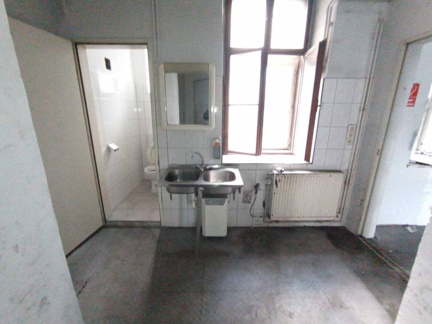 Sanitärbereich mit zwei Waschbecken, einem Fenster, Fliesen und einer Duschkabine im Hintergrund.