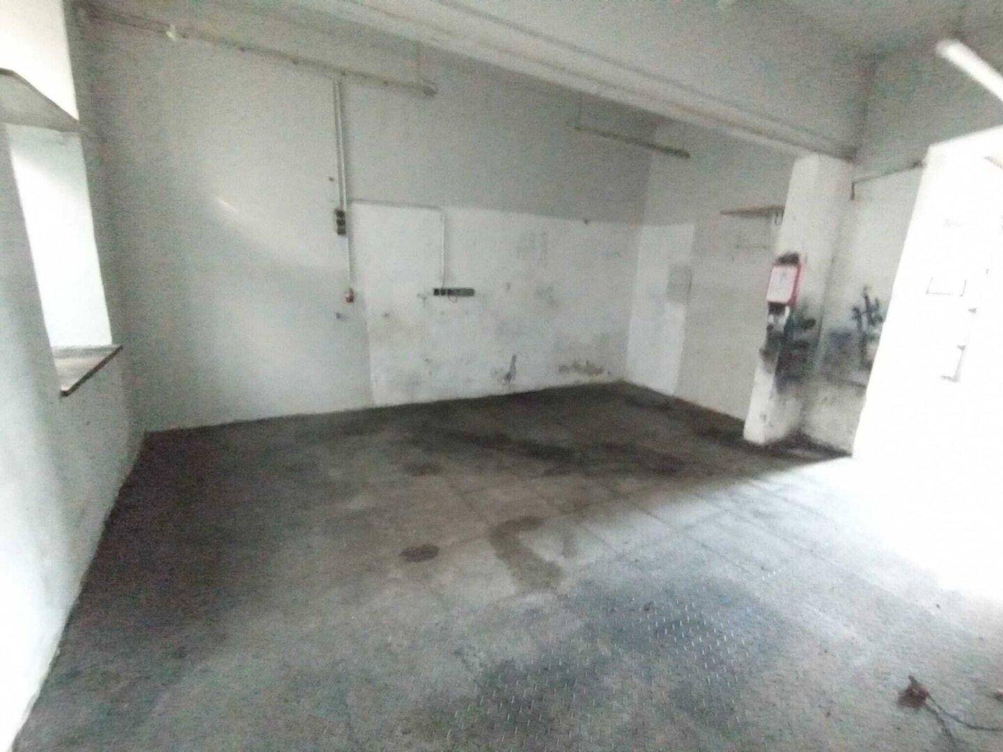 Einfacher Lagerraum mit Betonboden und weißen Wänden, der für verschiedene Zwecke genutzt werden kann.
