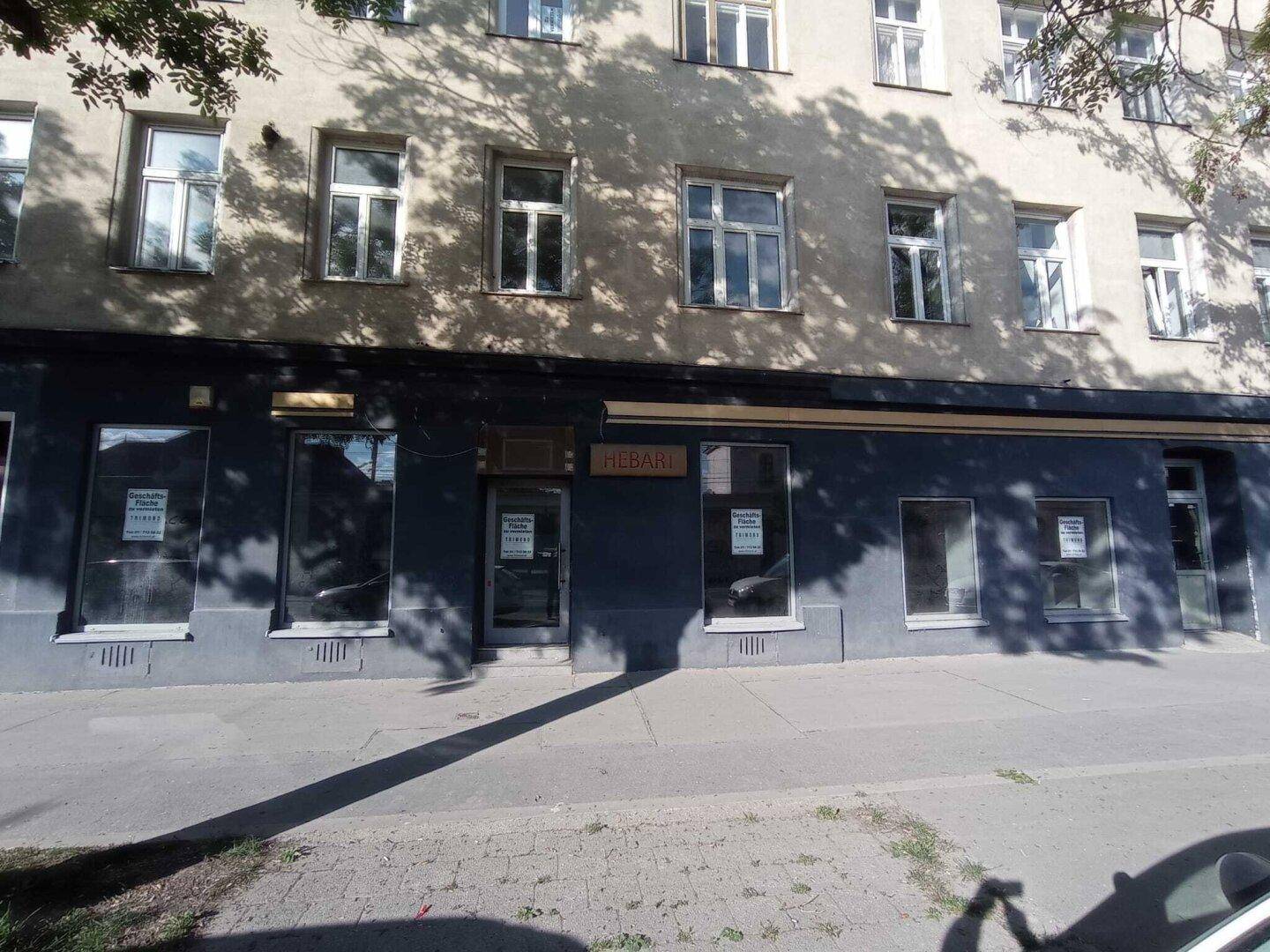 Außenansicht eines Geschäftsgebäudes mit mehreren Schaufenstern und einem "Hebart"-Schild an der Fassade.