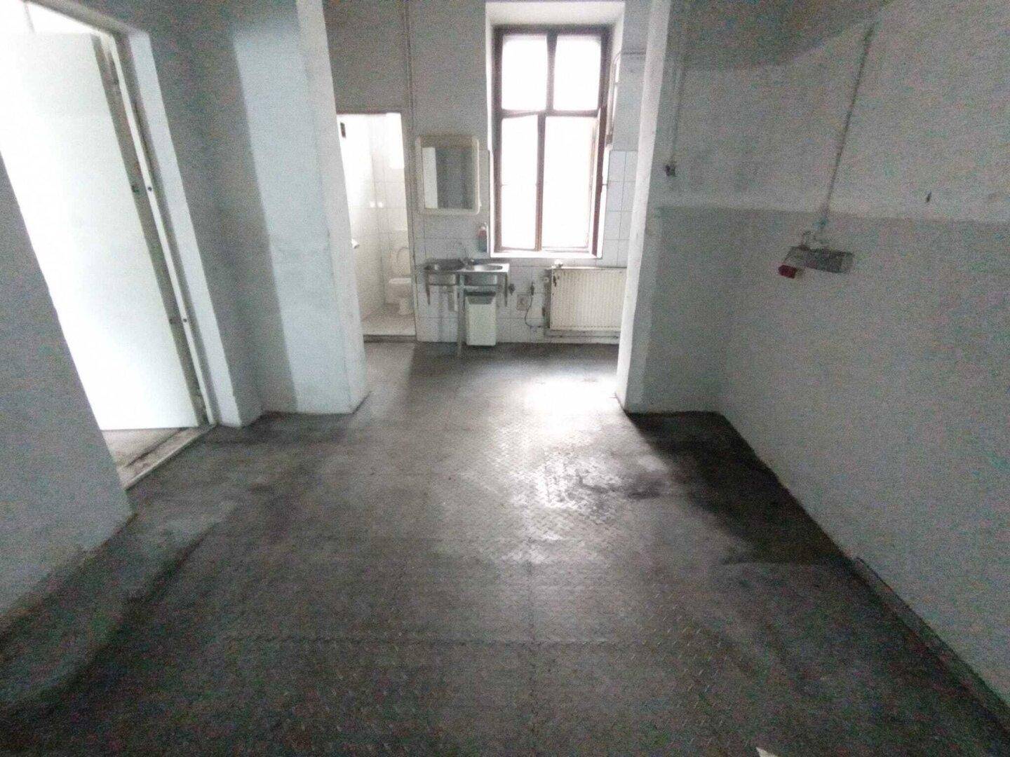 Einfacher Sanitärbereich mit zwei Waschbecken, einem Fenster und Fliesen an den Wänden.