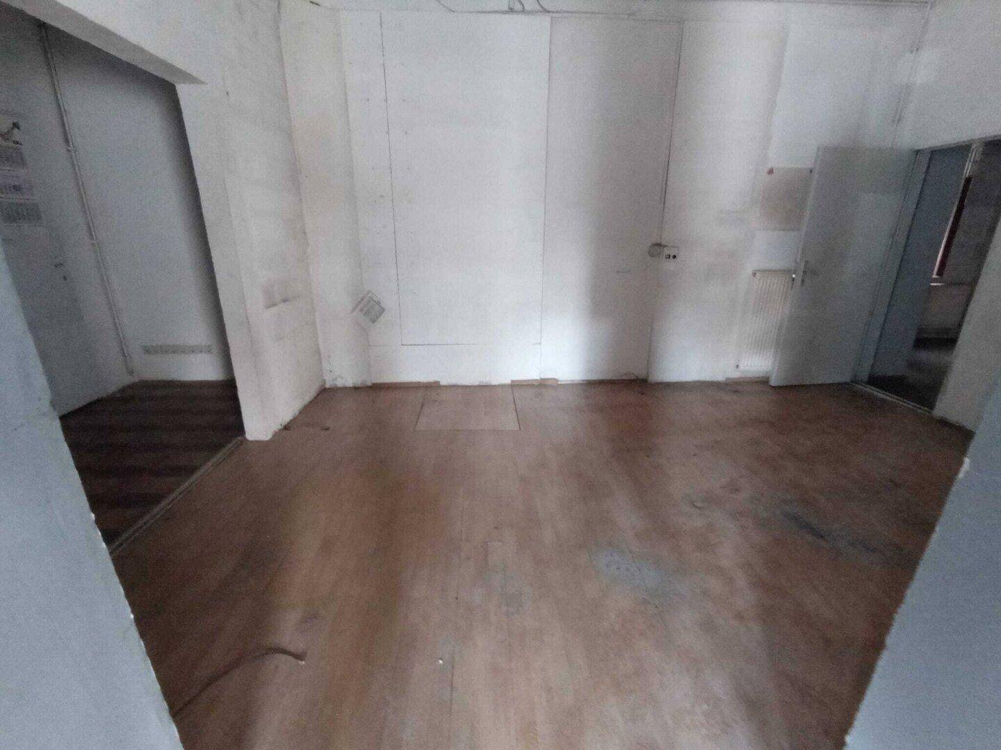 Geräumiger Geschäftsraum mit Holzboden und weißen Wänden, der vielseitig nutzbar ist.