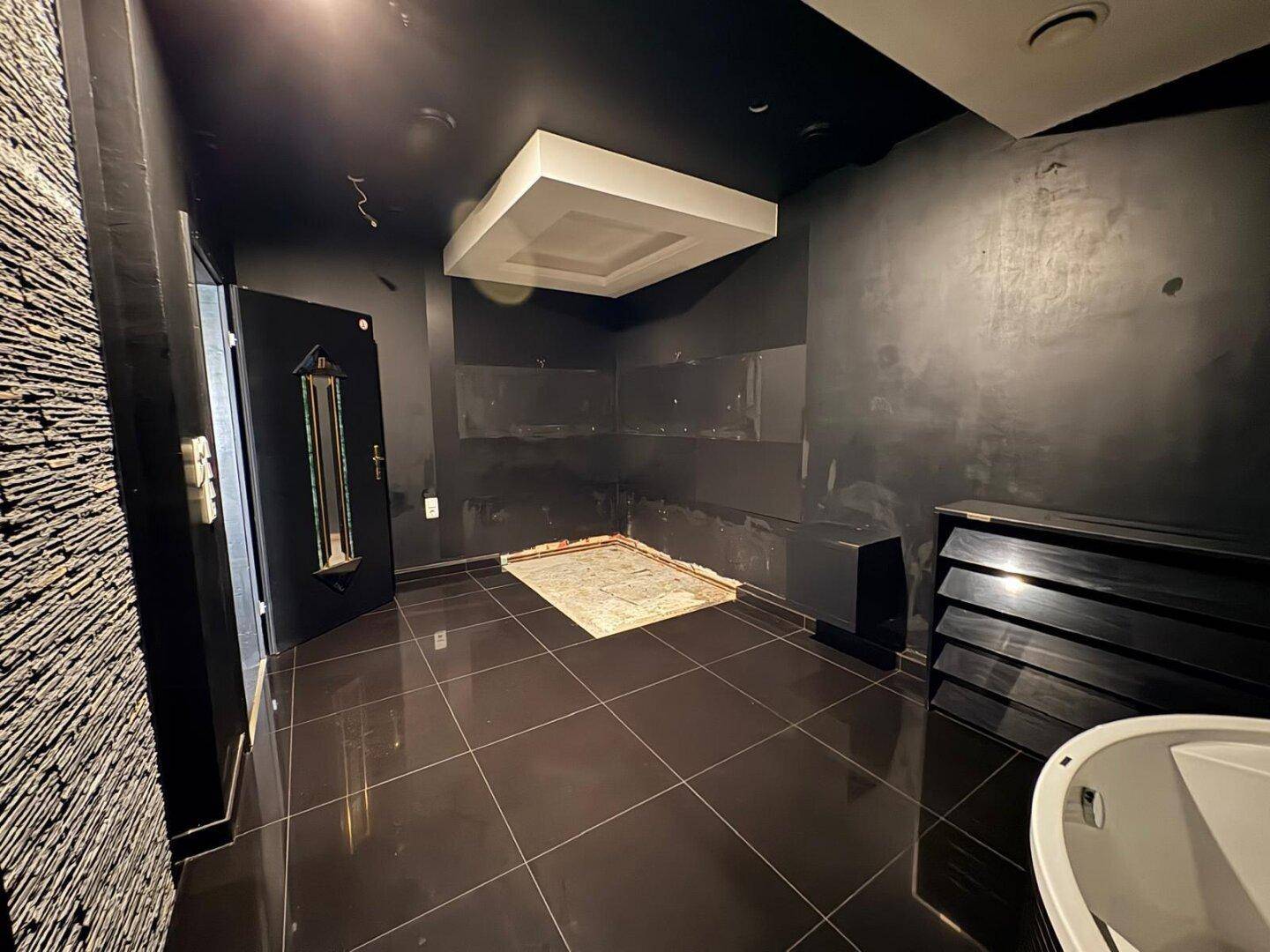 Badezimmer mit dunklen Fliesen und einer leeren Nische, bereit für weitere Ausstattung.