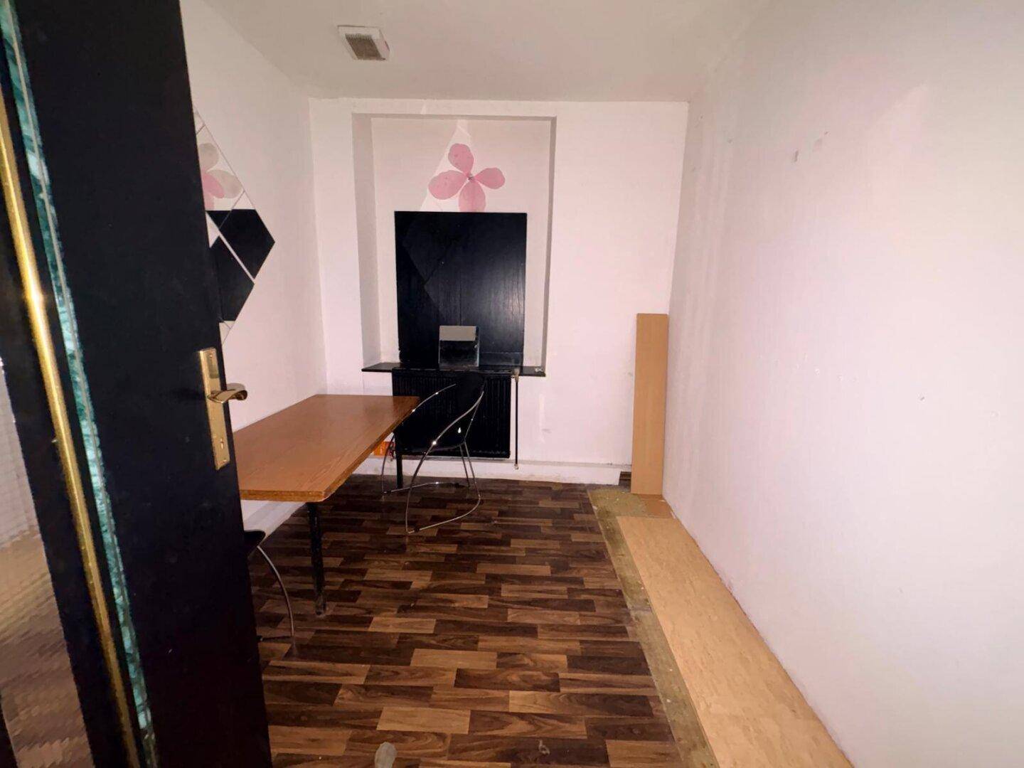 Hellerer Blick auf den Schreibtischbereich in einem Raum mit Holzboden und weiß gestrichenen Wänden.