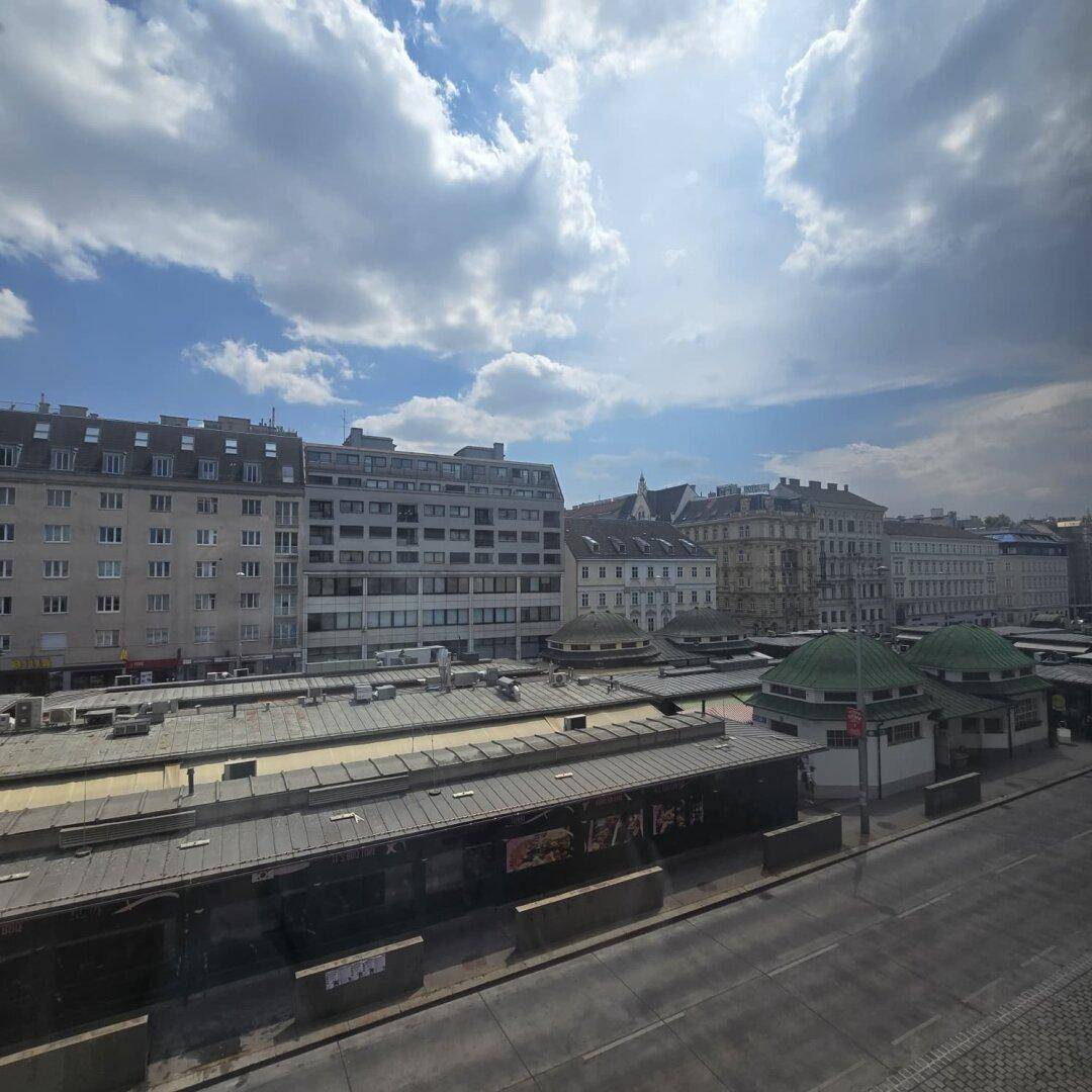 Stadtansicht mit Gebäuden und einer Straße unter einem bewölkten Himmel, der die Umgebung beleuchtet.