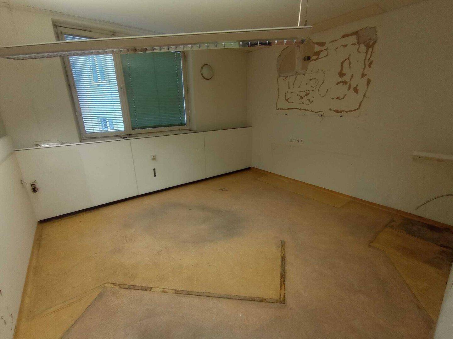 Raum mit Fenster und Deckenleuchte, die Wände zeigen Renovierungsbedarf, aber viel Potenzial für Neues.