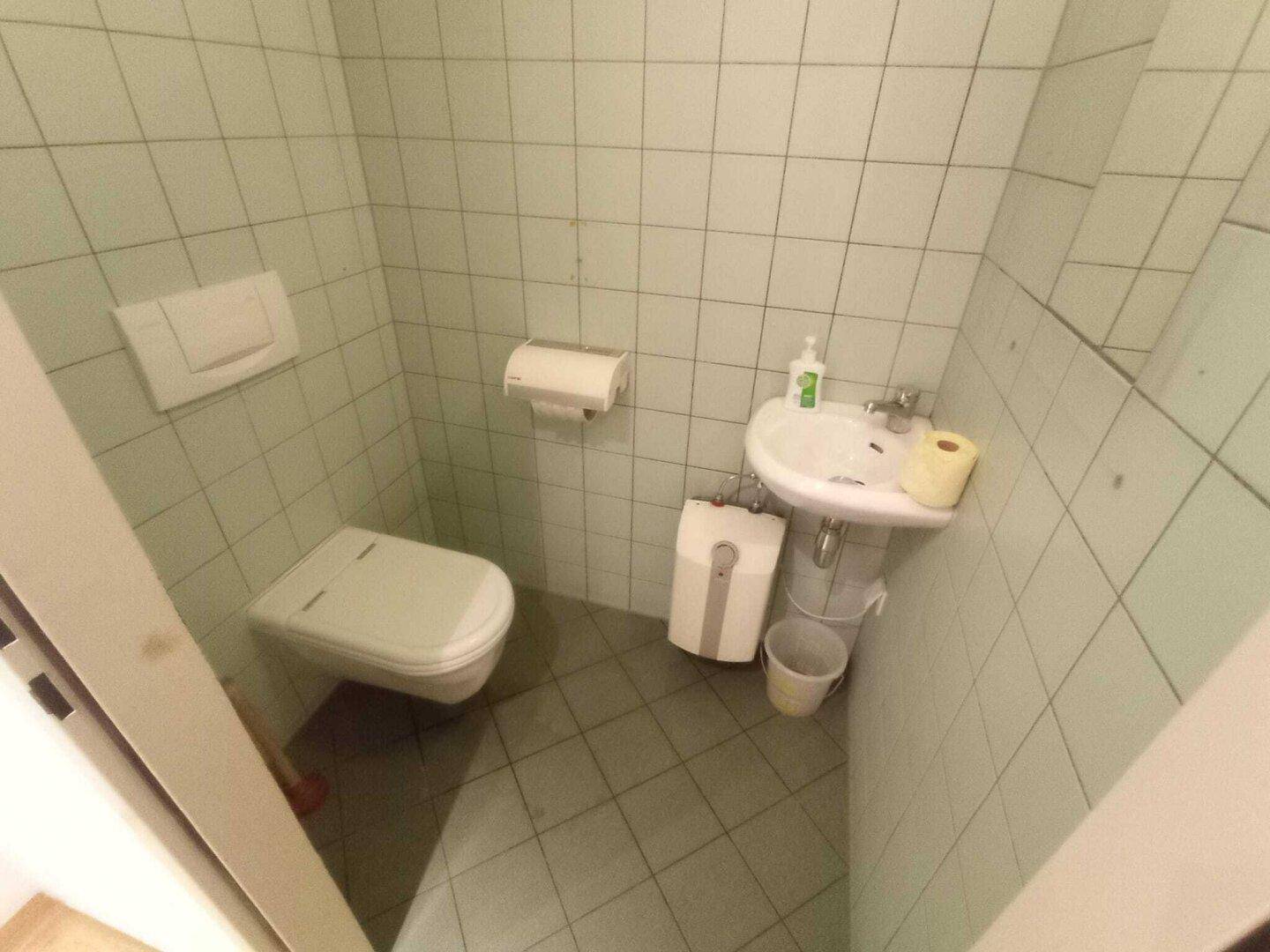 Nahaufnahme des Gäste-WCs mit Wand-WC und kleinem Waschbecken, in gutem und gepflegtem Zustand.