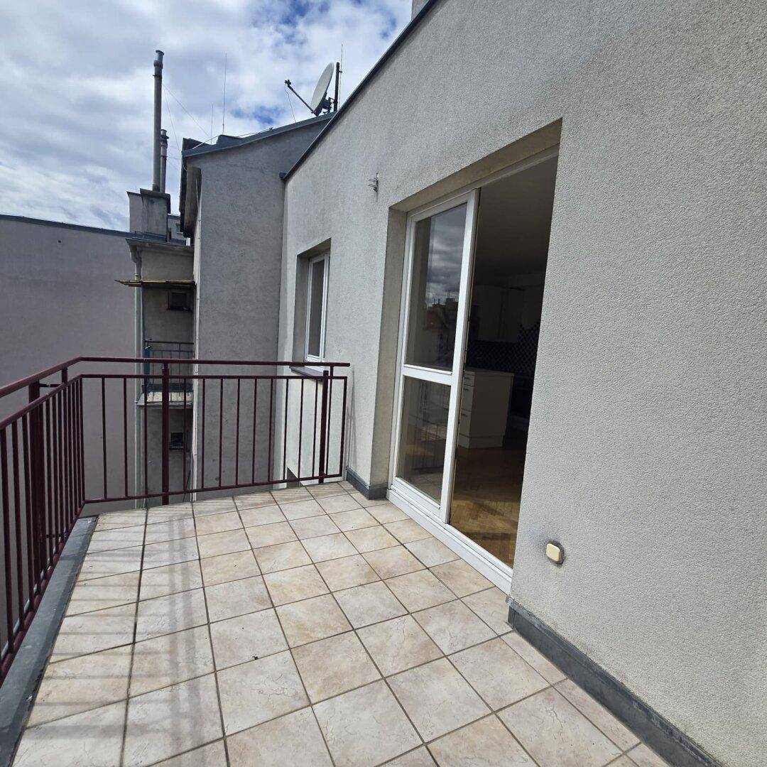 Balkon mit Fliesenboden und Zugang zu einem hellen Innenraum durch eine große Glasschiebetür.