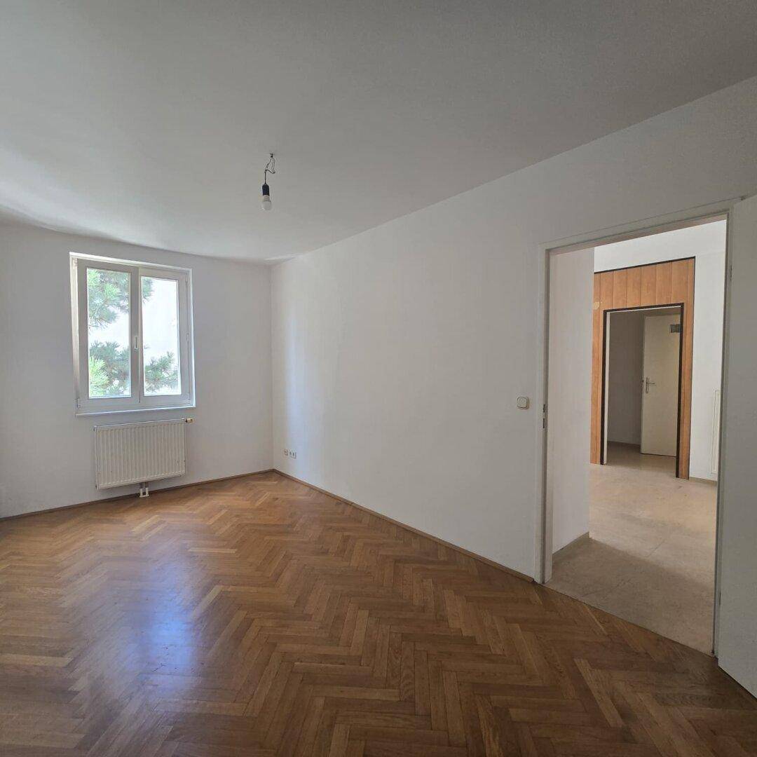 Helles Wohnzimmer mit klassischem Fischgrätparkett und weiß gestrichenen Wänden.
