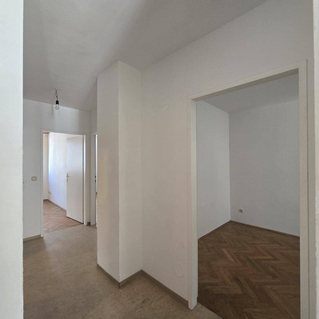 Heller Flur mit schlichten Wänden und Zugängen zu den angrenzenden Wohnbereichen.