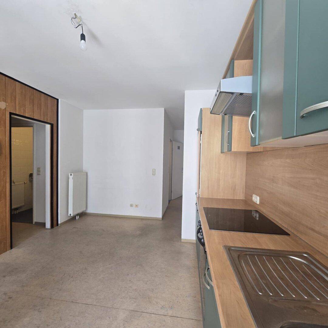 Blick von der Küche in den Flur, zeigt Arbeitsplatte und Kochfeld der Einbauküche.