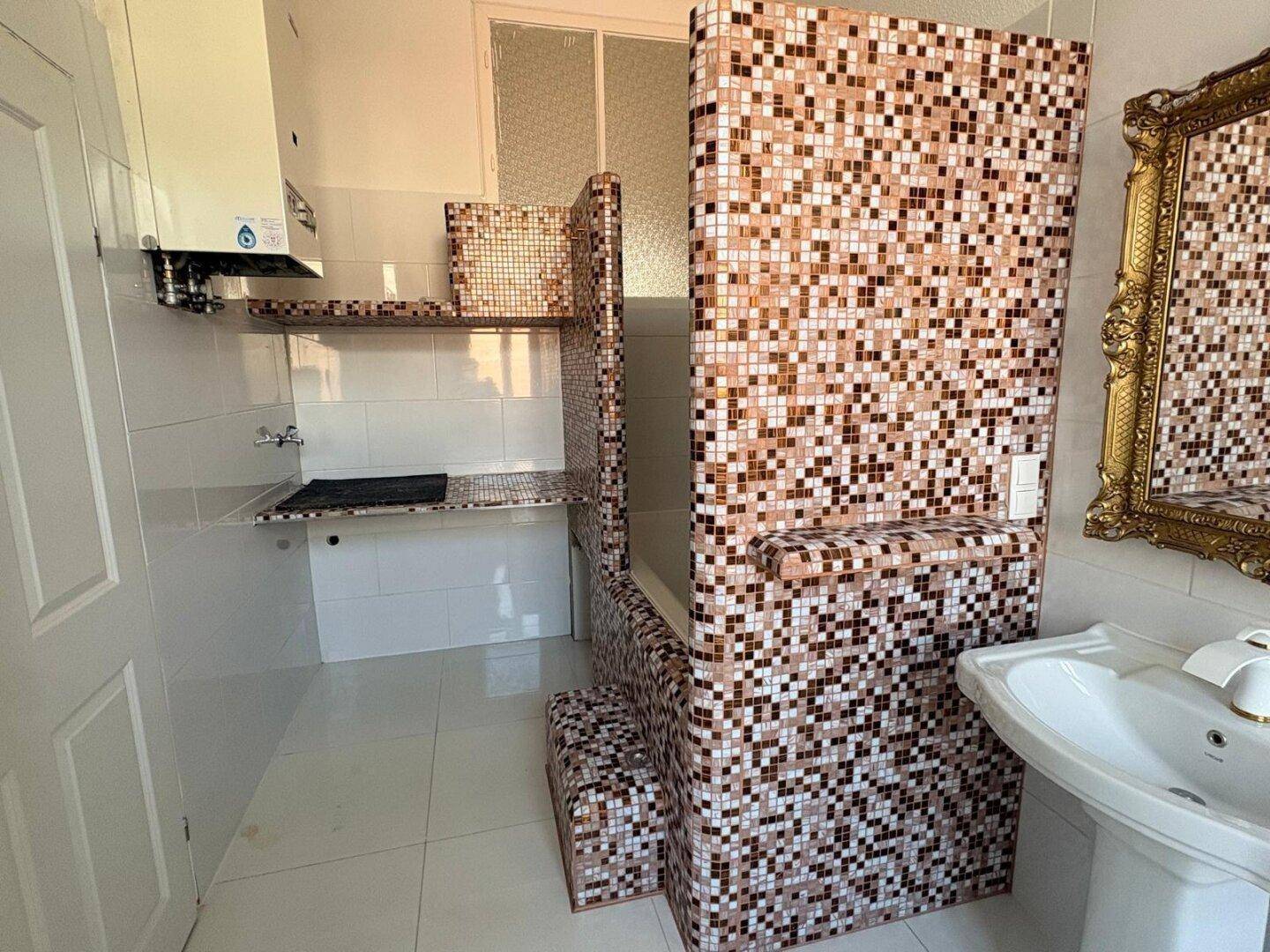Badezimmer mit Badewanne, Mosaikfliesen und einem Wandspiegel.