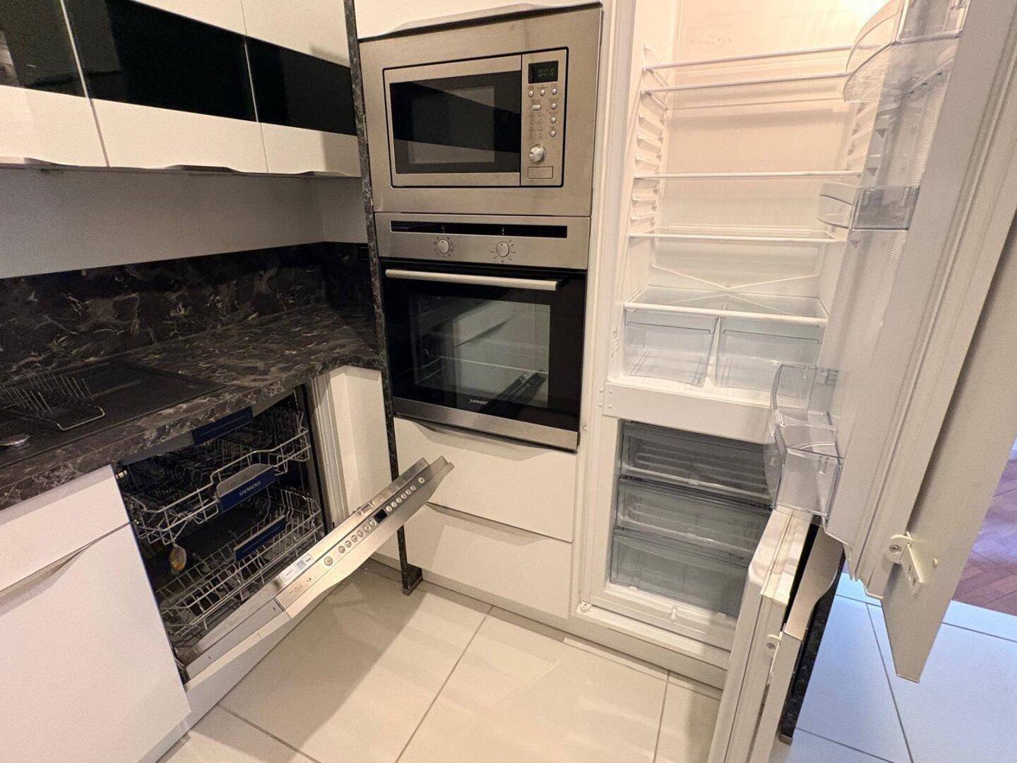 Einbauküche mit integriertem Kühlschrank, Geschirrspüler, Backofen und Mikrowelle.