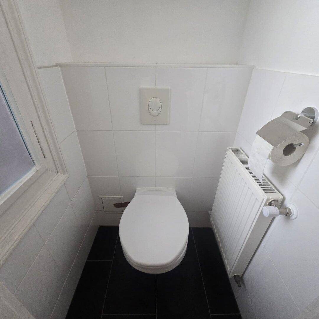 Kleines Gäste-WC mit Toilette, Heizkörper und einem Fenster für natürliche Belüftung.