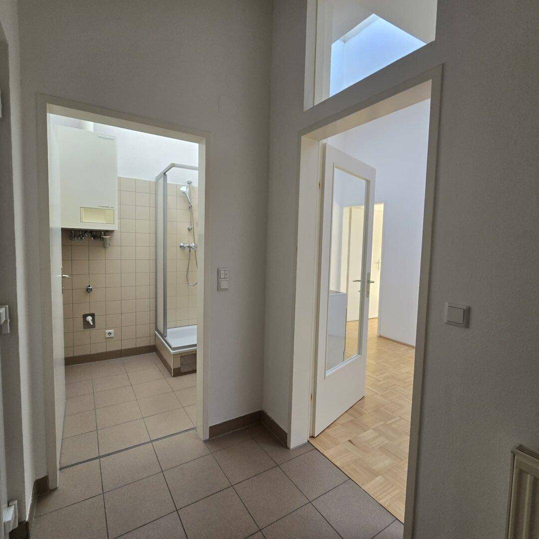 Flur mit Fliesenboden, der zu einem Badezimmer und einem weiteren Wohnbereich führt.