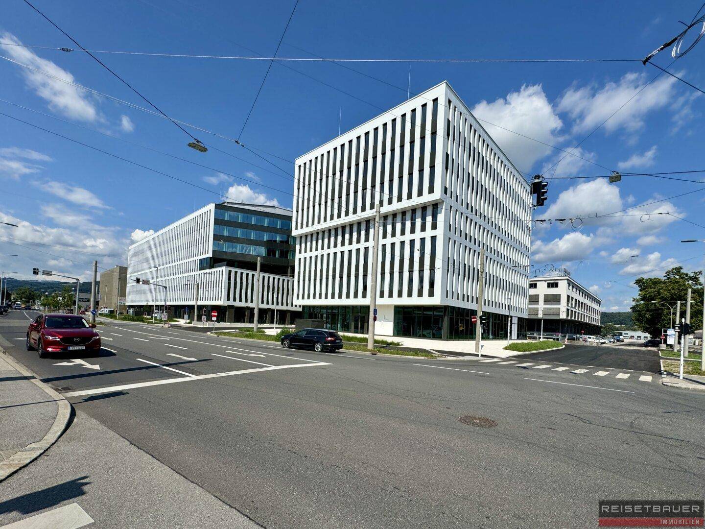 Das moderne Geschäftsgebäude präsentiert sich mit seiner charakteristischen Fassade an einer belebten Kreuzung.
