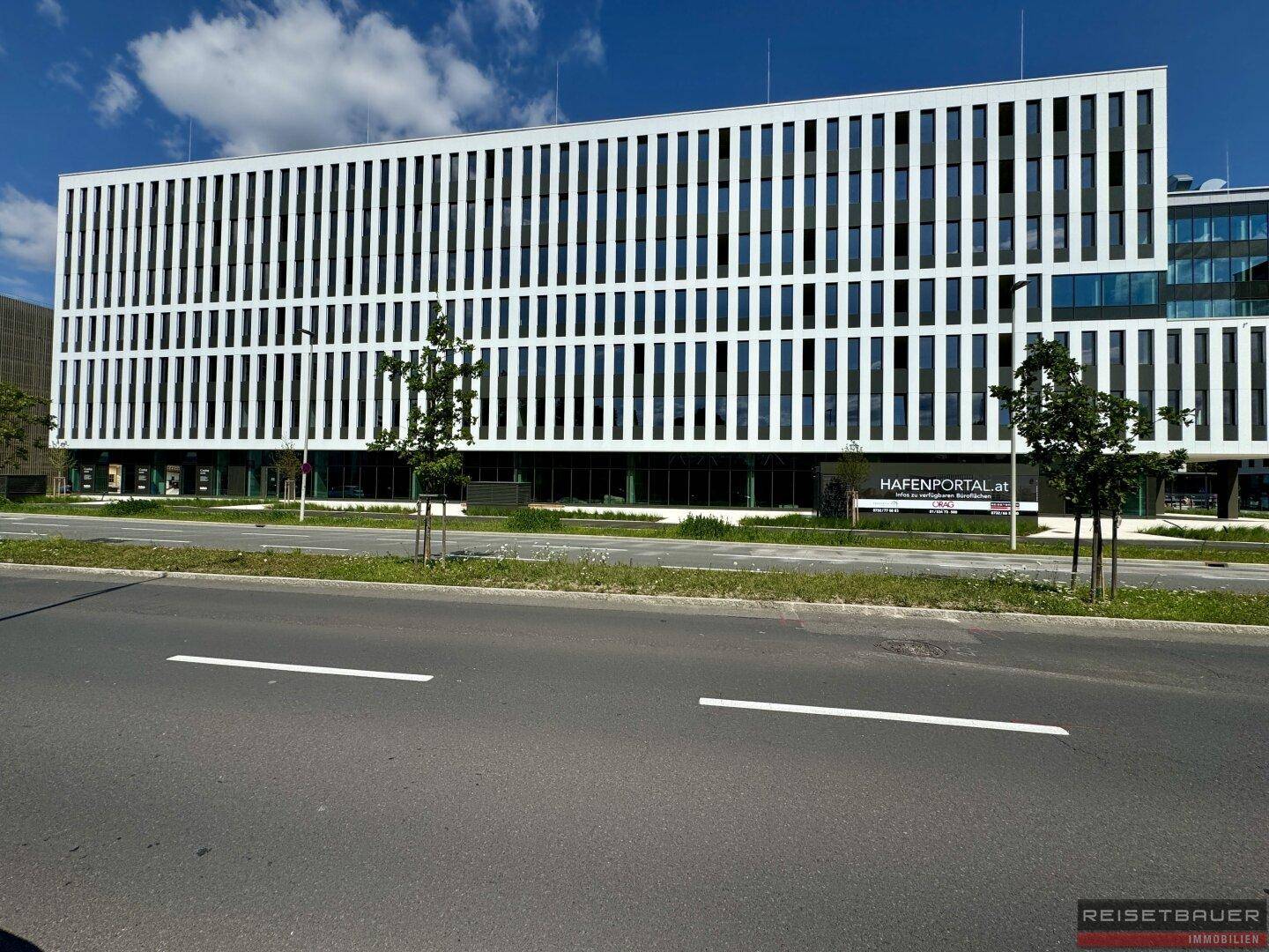Breite Ansicht der modernen Bürogebäude-Fassade mit vertikalen Elementen und großen Fensterflächen.