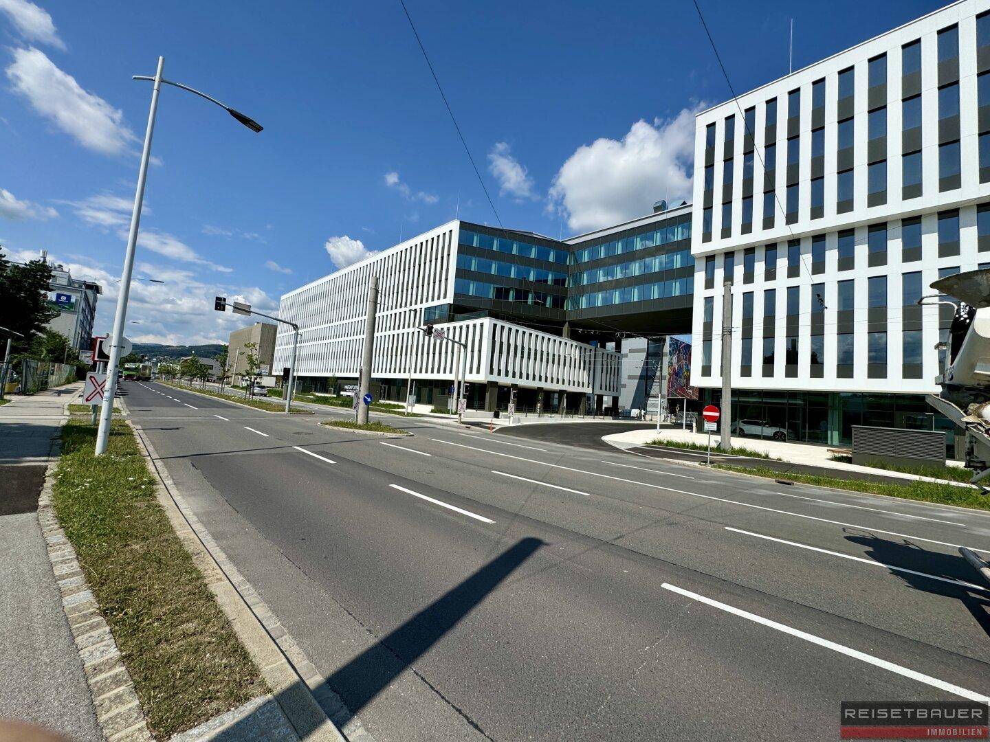 Weitläufige Ansicht des modernen Gebäudekomplexes mit umliegender Infrastruktur und Straße.