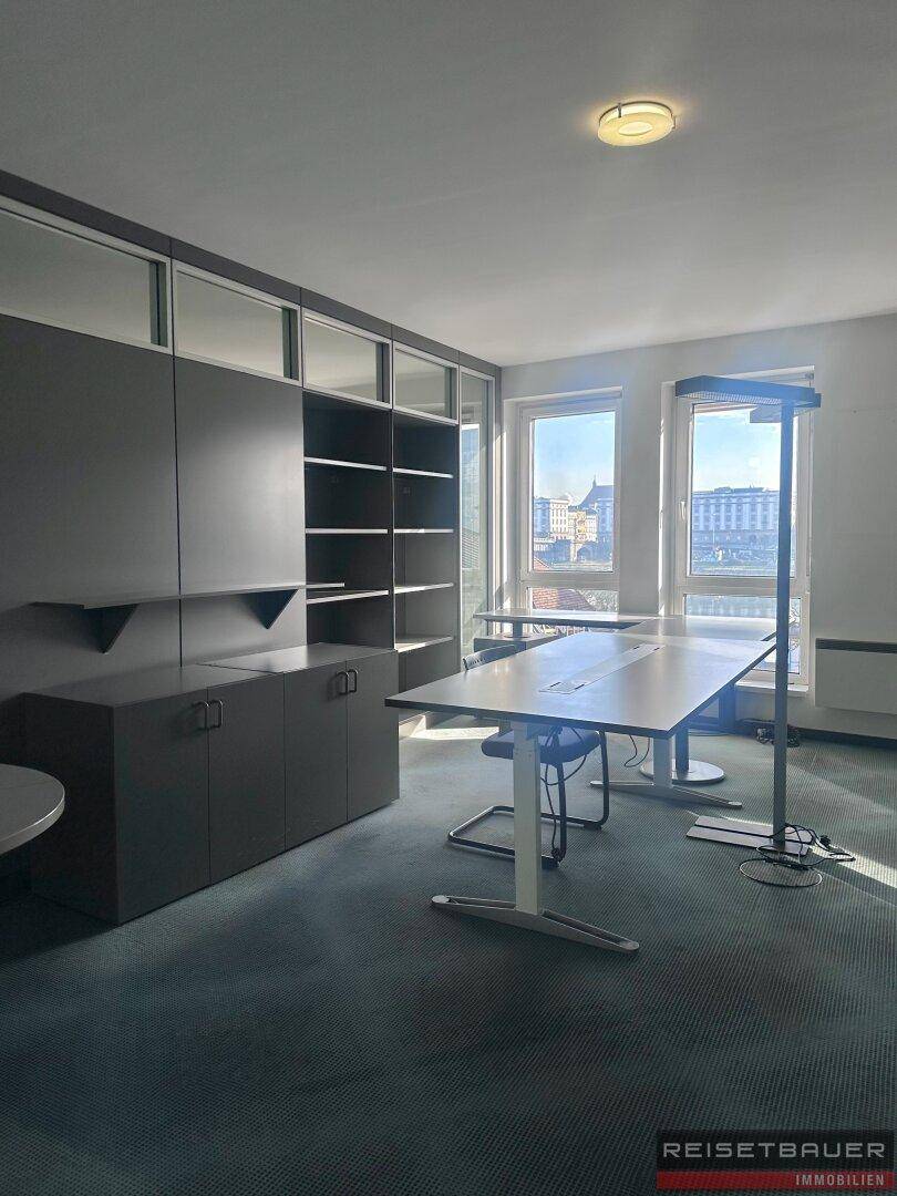 Modernes Büro mit Teppichboden, Einbauschränken und Blick auf die Stadt.