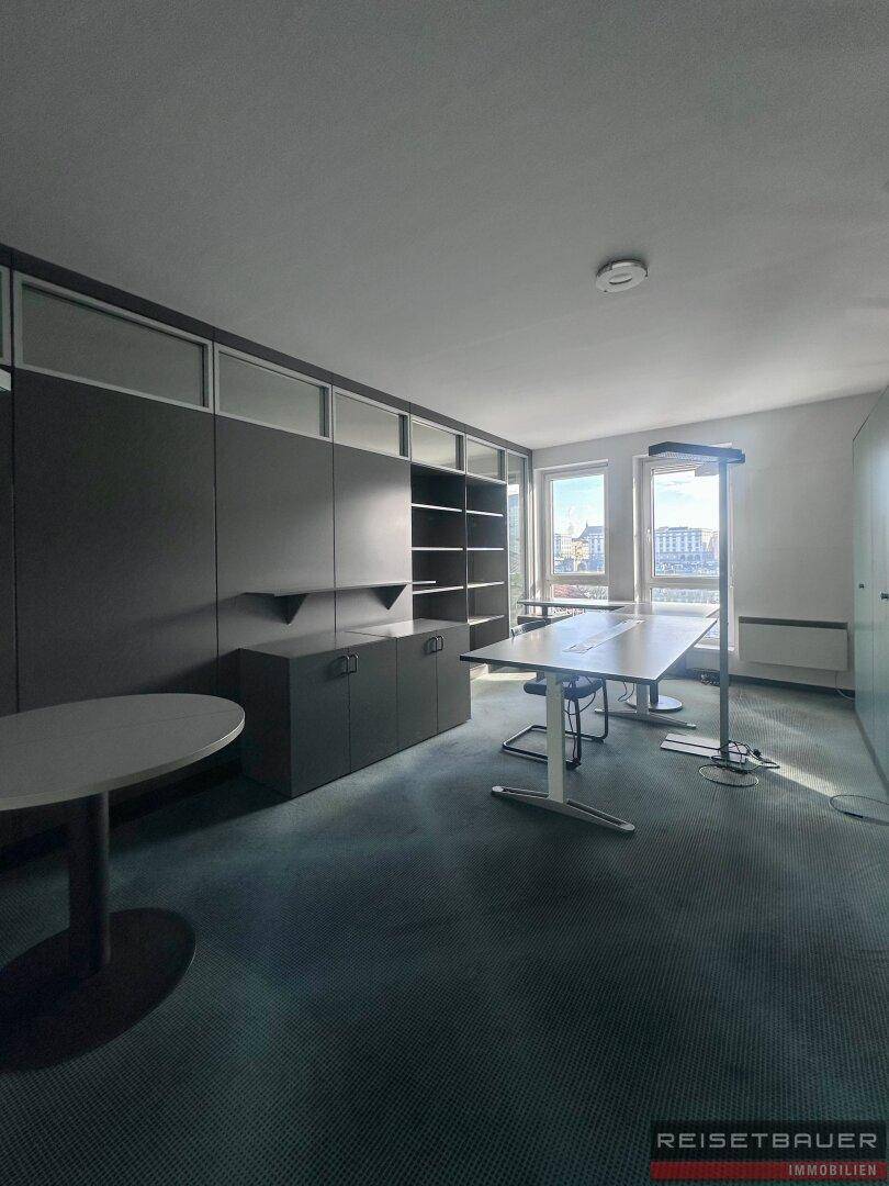 Modernes Büro mit Teppichboden, Einbauschränken und Blick auf die Stadt.