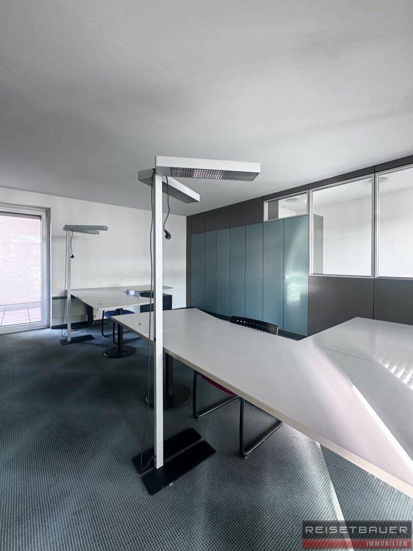 Helles Büro mit Teppichboden, mehreren Arbeitsplätzen und Einbauschränken.