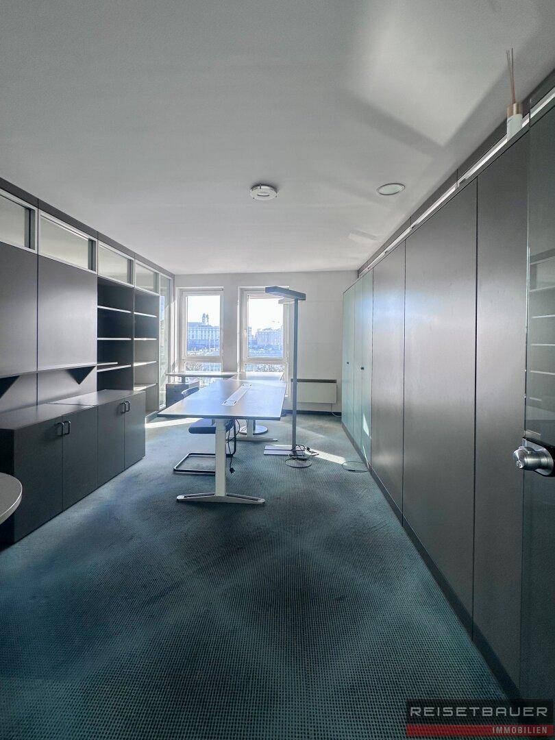 Modernes Büro mit Teppichboden, Einbauschränken und Blick auf die Stadt.