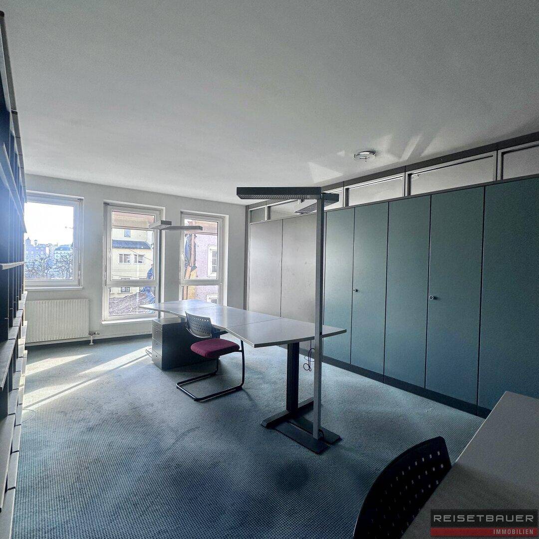 Geräumiges Büro mit Teppichboden, Einbauschränken und Blick auf die Stadt.