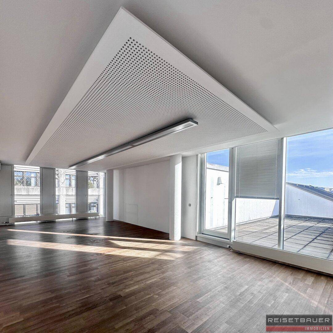 Geräumiges Büro mit Holzboden, großen Fenstern und Zugang zu einer Dachterrasse.