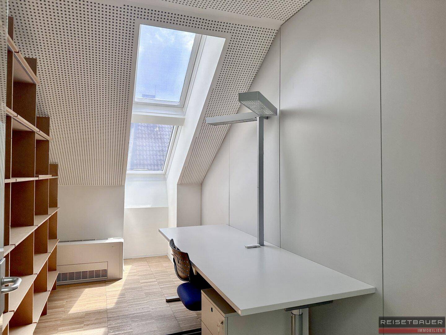 Dachgeschossbüro mit schrägen Wänden, Dachfenster und einem Arbeitsplatz mit Schreibtisch.