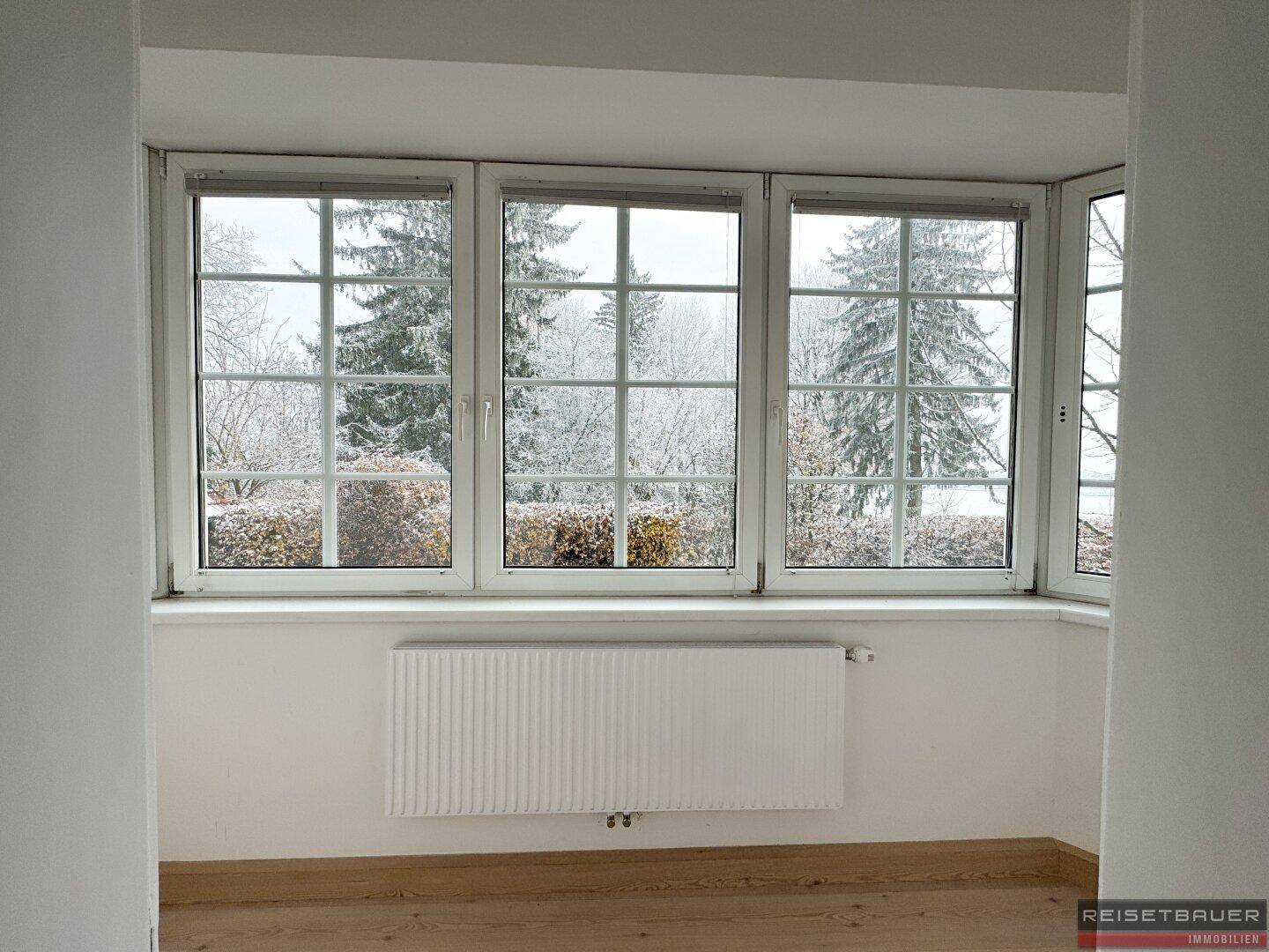 Fensterfront mit Blick auf verschneite Bäume, bietet viel natürliches Licht im Raum.