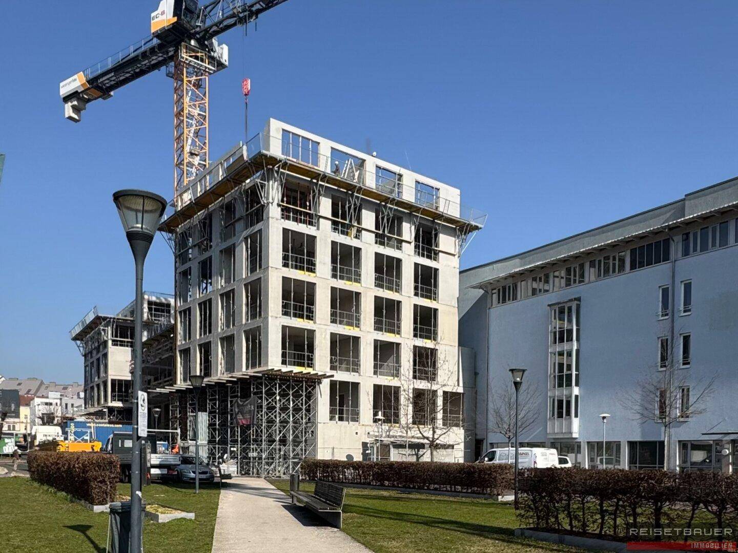 Neubau in der Bauphase mit sichtbarer Betonkonstruktion und Kran im Hintergrund.