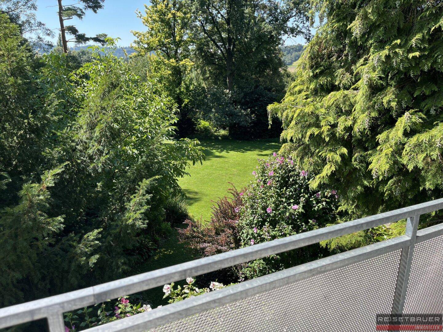 Balkon mit Blick auf den weitläufigen, grünen Garten und die umliegende Landschaft.
