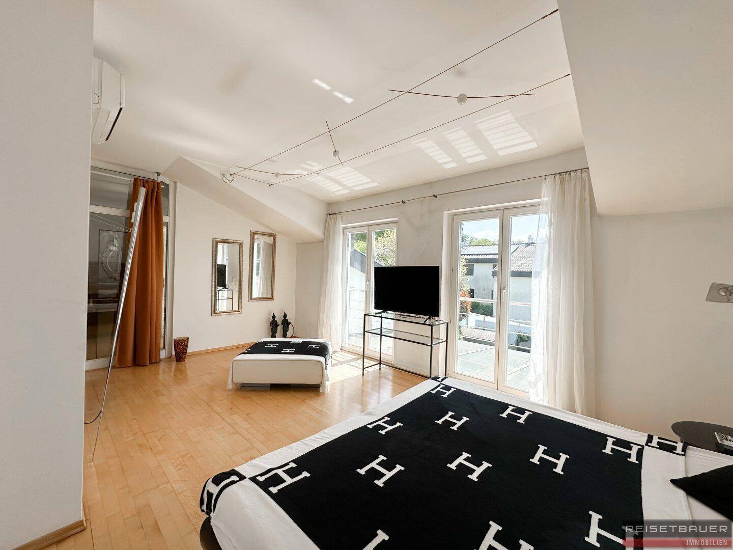 Modernes Schlafzimmer mit Holzboden, Klimaanlage und Zugang zu einem Balkon oder einer Terrasse.