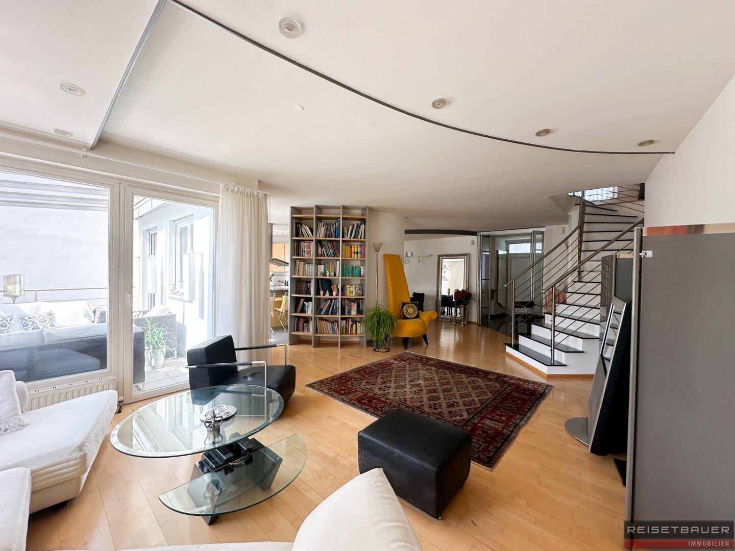 Helles Wohnzimmer mit Holzboden, gemütlicher Sitzecke und Zugang zu einer Außenterrasse.