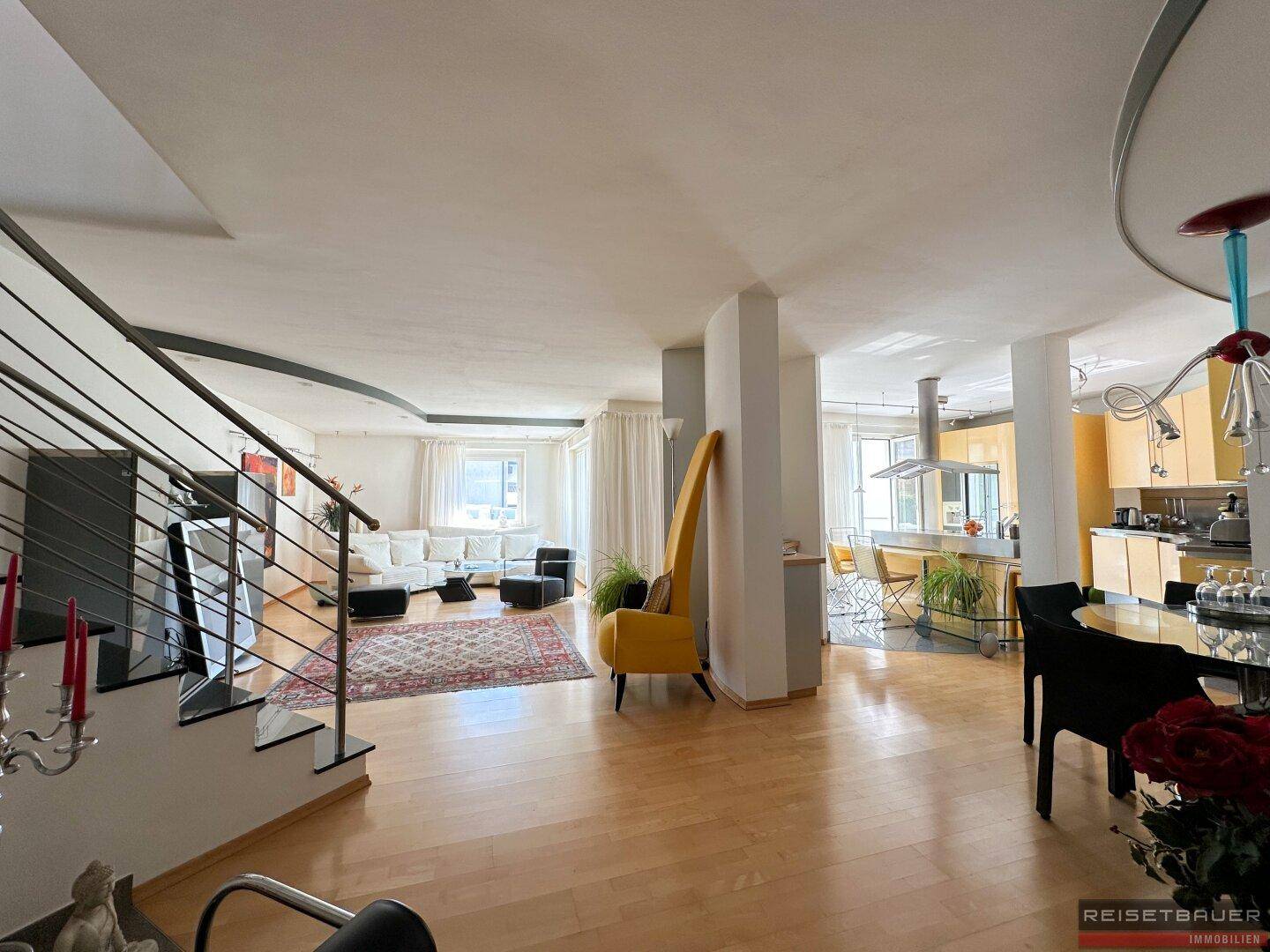 Großzügiger offener Wohn- und Essbereich mit Holzboden und moderner Treppe, die verschiedene Ebenen verbindet.