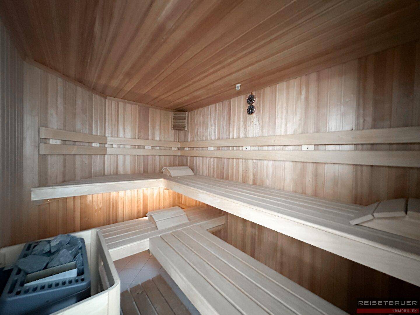Moderne Holzsauna mit mehreren Bänken und einem Saunaofen, ideal zur Entspannung.