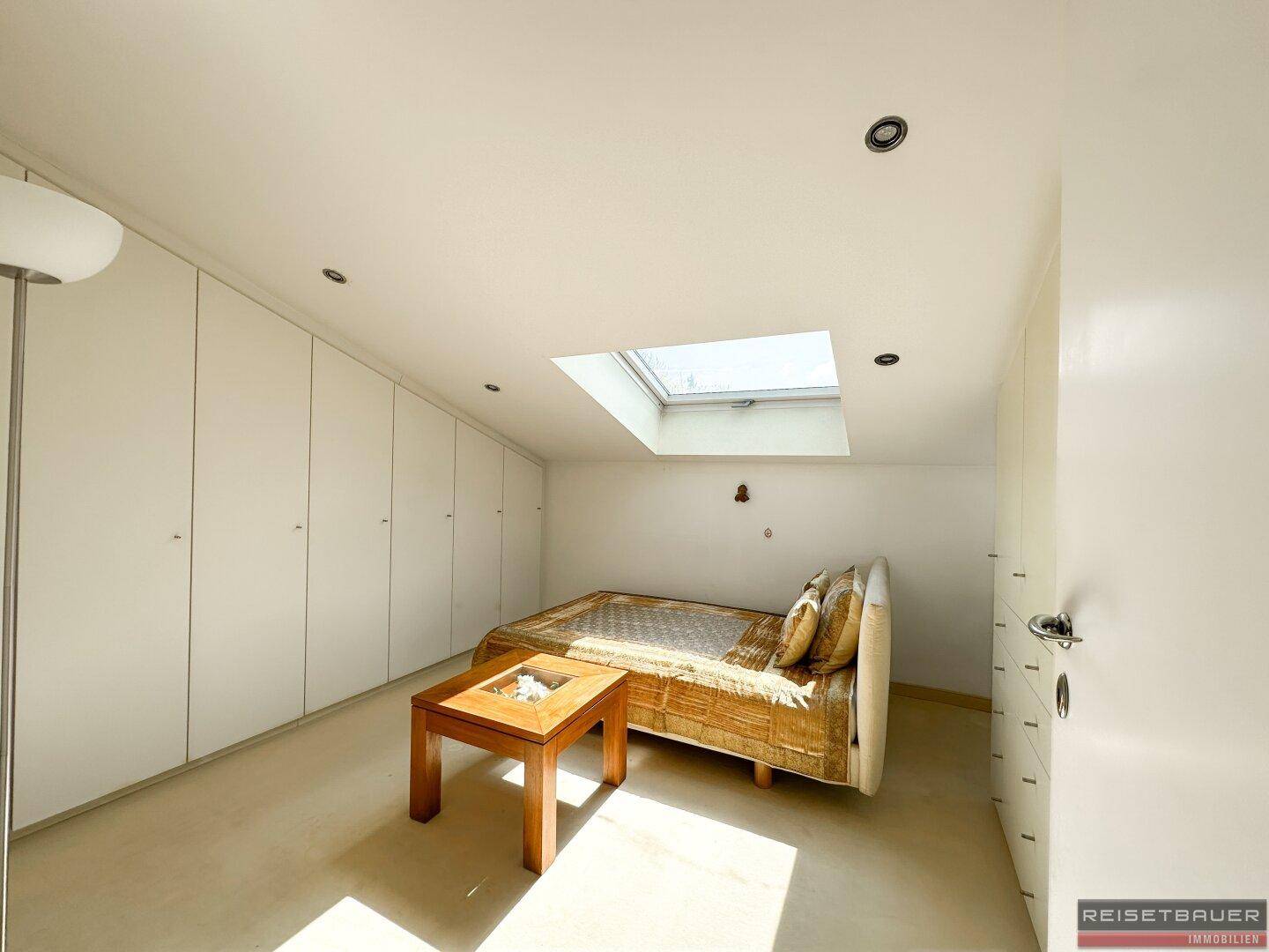 Gemütliches Schlafzimmer mit Einbauschränken, Teppichboden und einem Dachfenster für natürliches Licht.