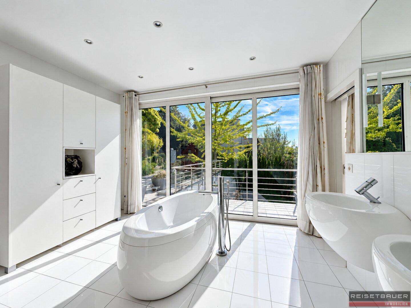 Modernes Badezimmer mit freistehender Badewanne, Bidet und großen Fensterfronten.