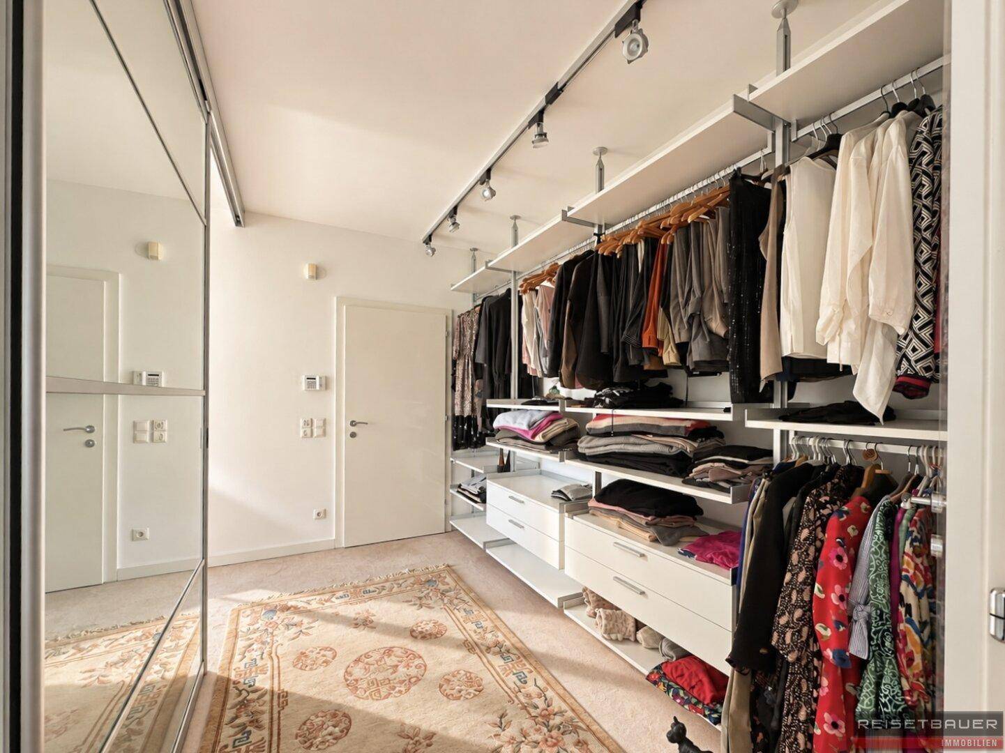 Großer begehbarer Kleiderschrank mit viel Stauraum und Spiegelfronten.