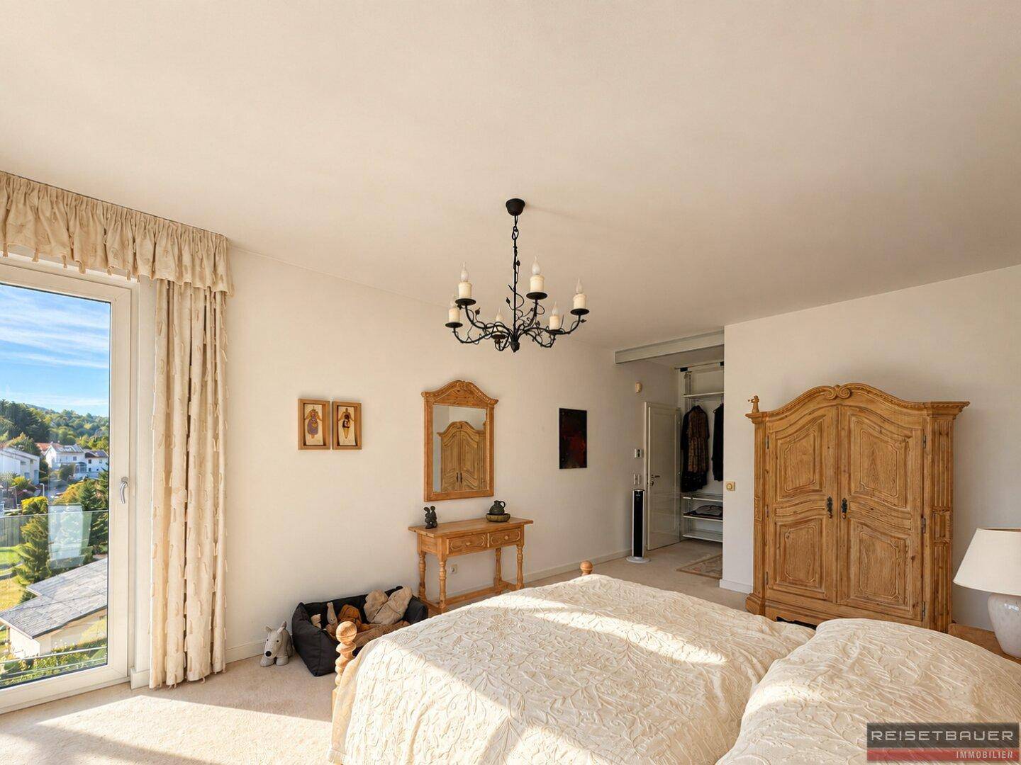 Helles Schlafzimmer mit traditionellen Holzmöbeln, Teppichboden und weitem Ausblick.