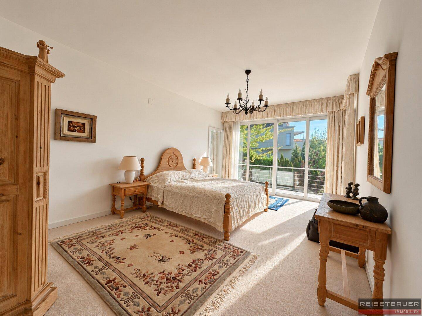 Geräumiges Schlafzimmer mit Teppichboden, Holzmöbeln und Zugang zu einem Balkon.