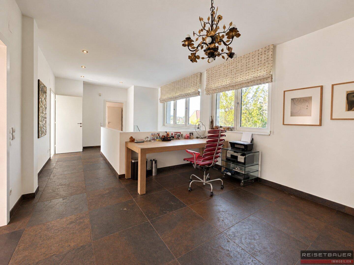 Helles Arbeitszimmer mit großem Schreibtisch, Fenstern und Blick ins Grüne.