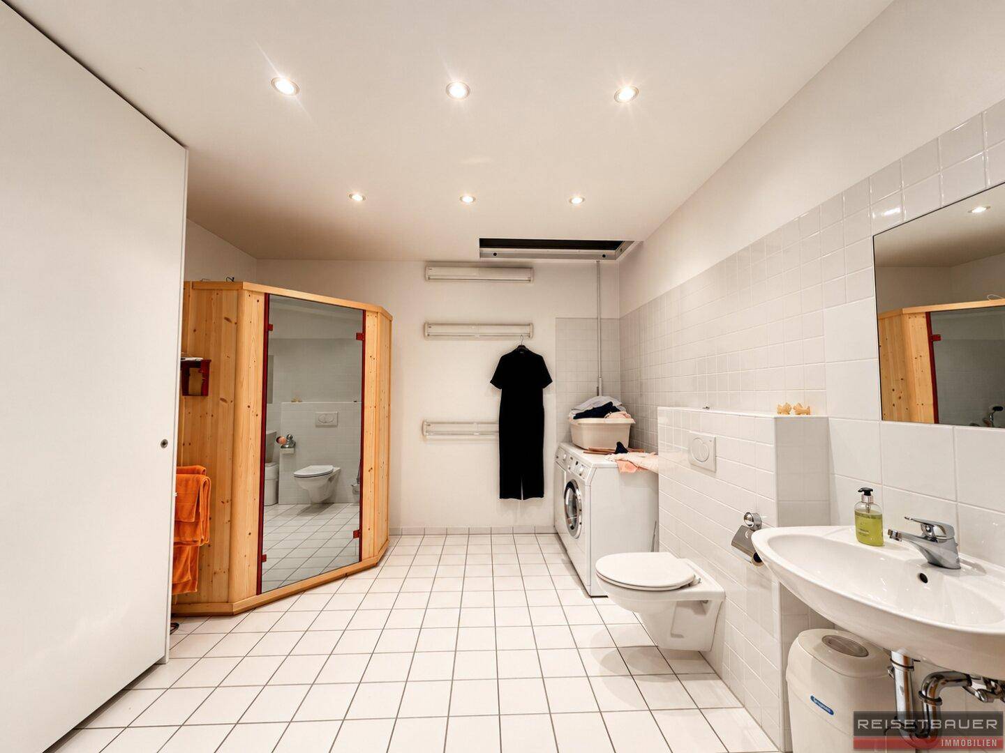 Großer Hauswirtschaftsraum mit Waschmaschine, WC, Waschbecken und integrierter Sauna.