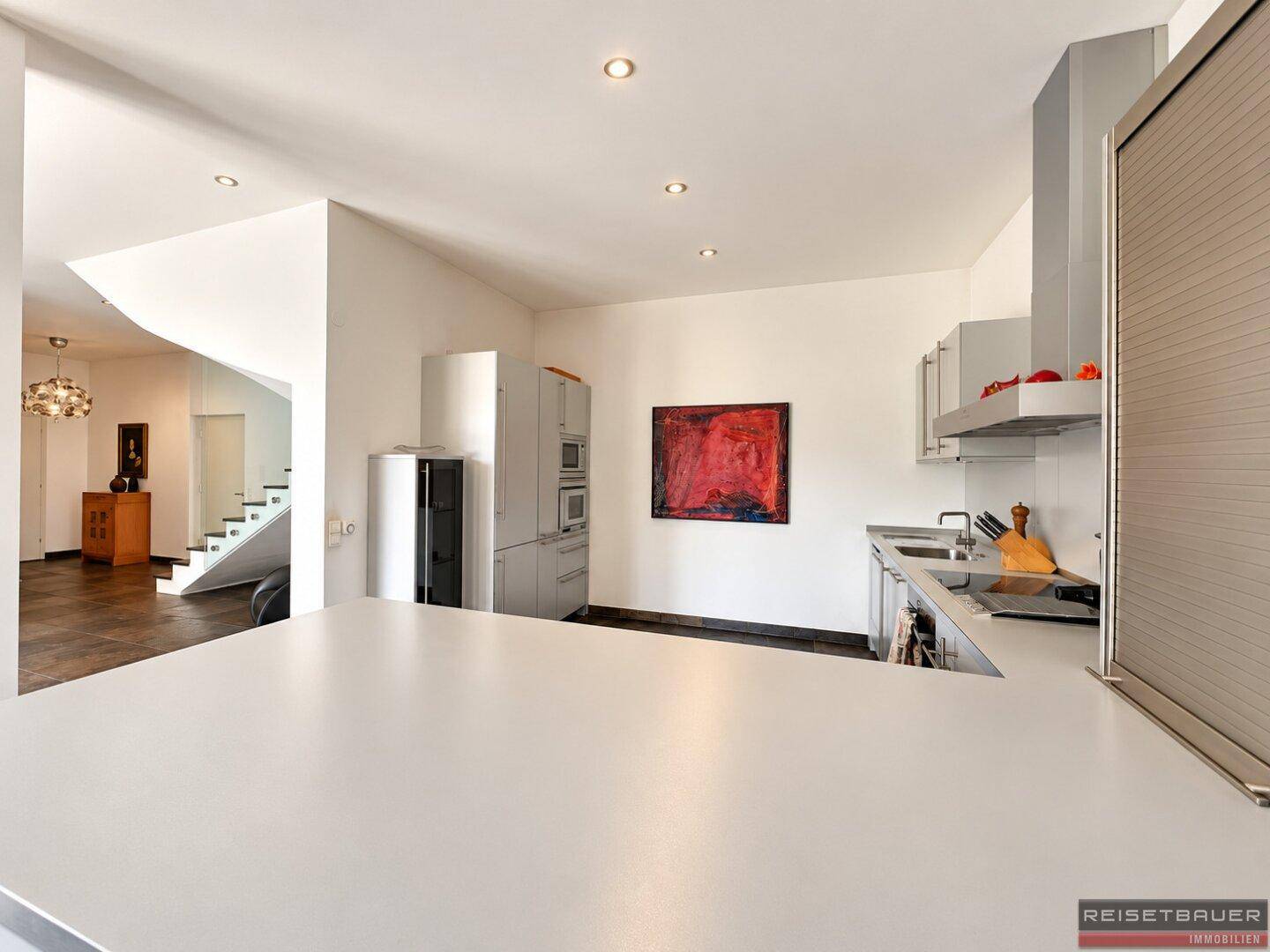 Geräumige Küche mit heller Arbeitsplatte, modernen Geräten und Blick auf den Wohnbereich.