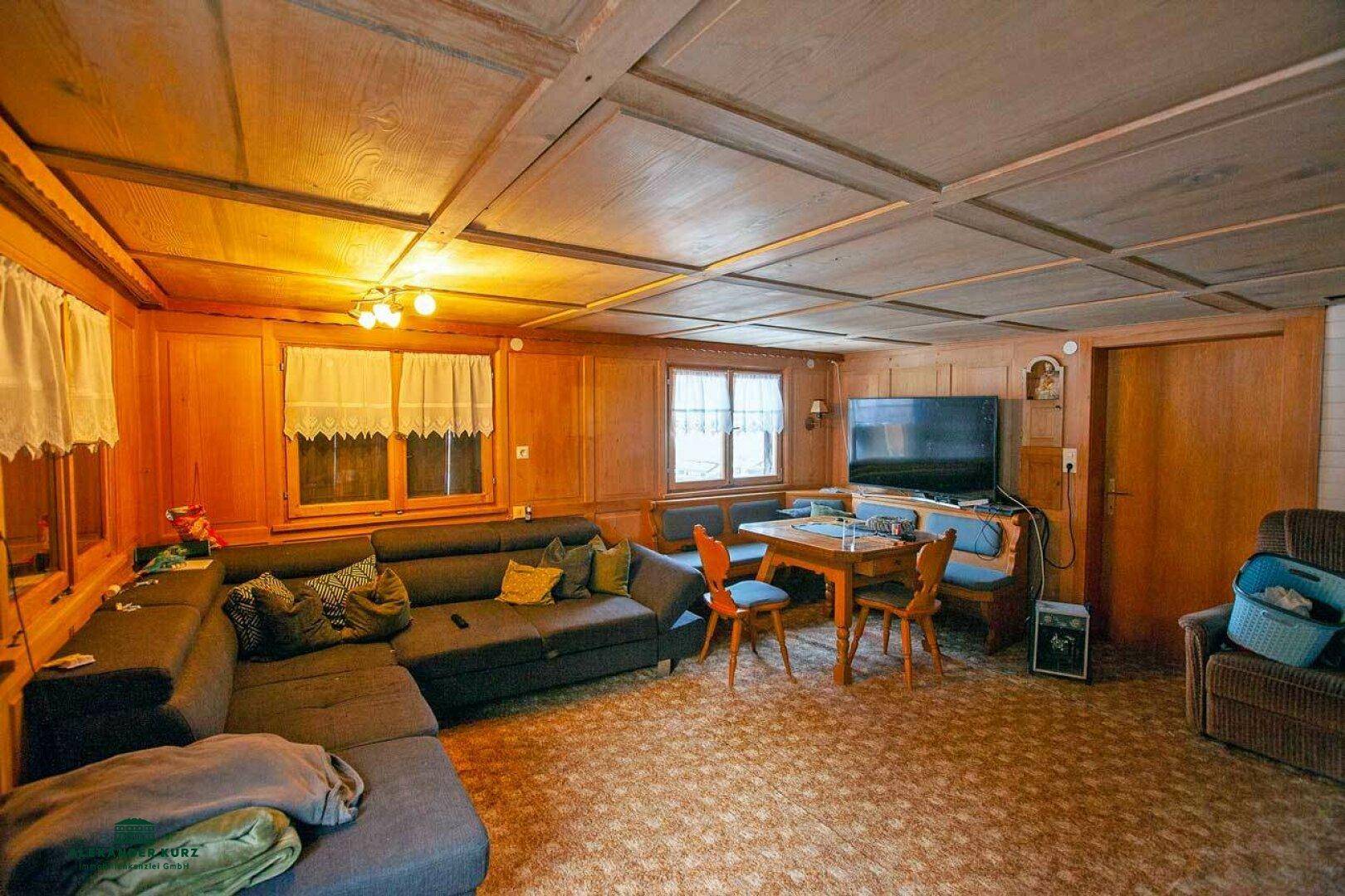 Rustikaler Wohn- und Essbereich mit Holztäfelung, gemütlichem Sofa und traditionellen Möbeln.