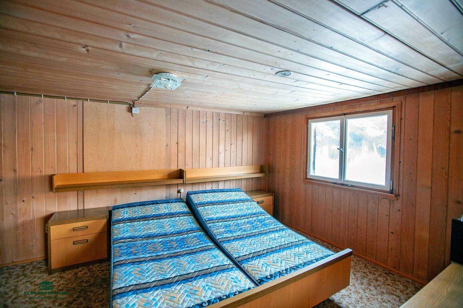 Gemütliches Schlafzimmer mit zwei Einzelbetten, Holzwänden und Teppichboden.