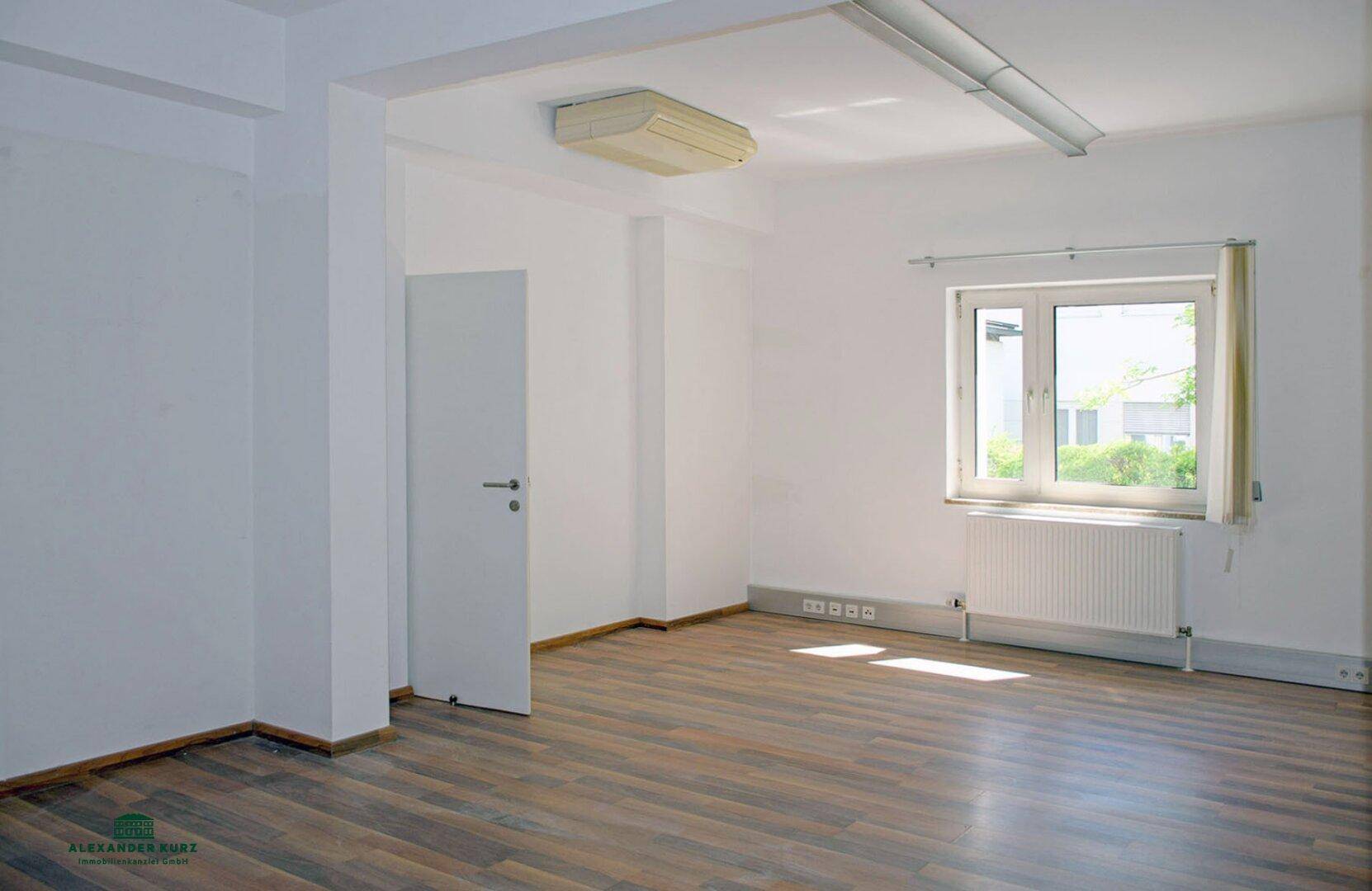 Geräumiger, leerer Raum mit Fenster, Heizkörper und Laminatboden, bietet vielseitige Nutzungsmöglichkeiten.