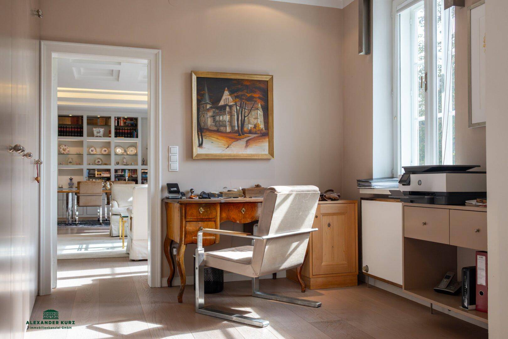 Ruhiges Arbeitszimmer mit Schreibtisch, Bürostuhl und Blick in den offenen Wohnbereich.